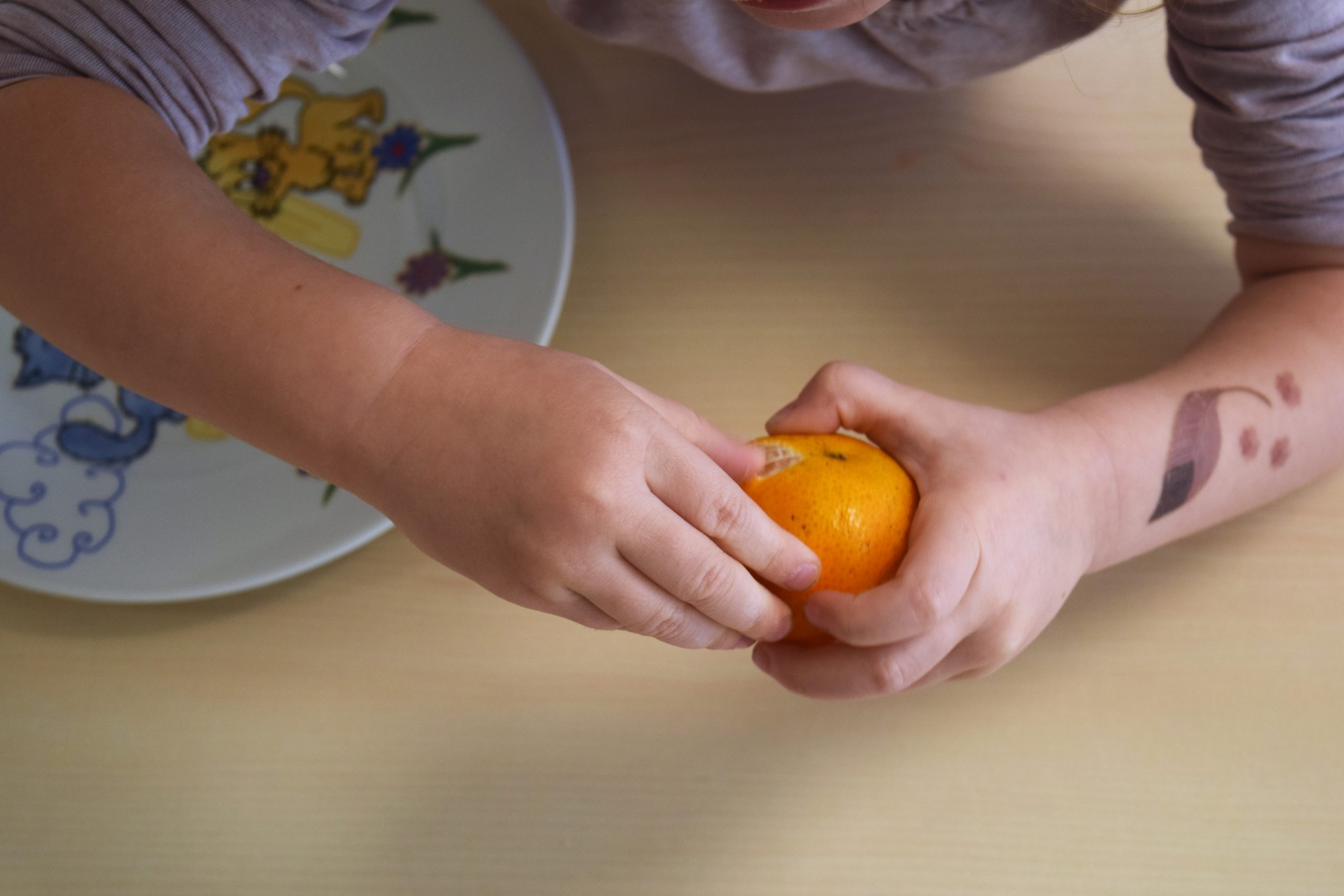 Kind schält Mandarine