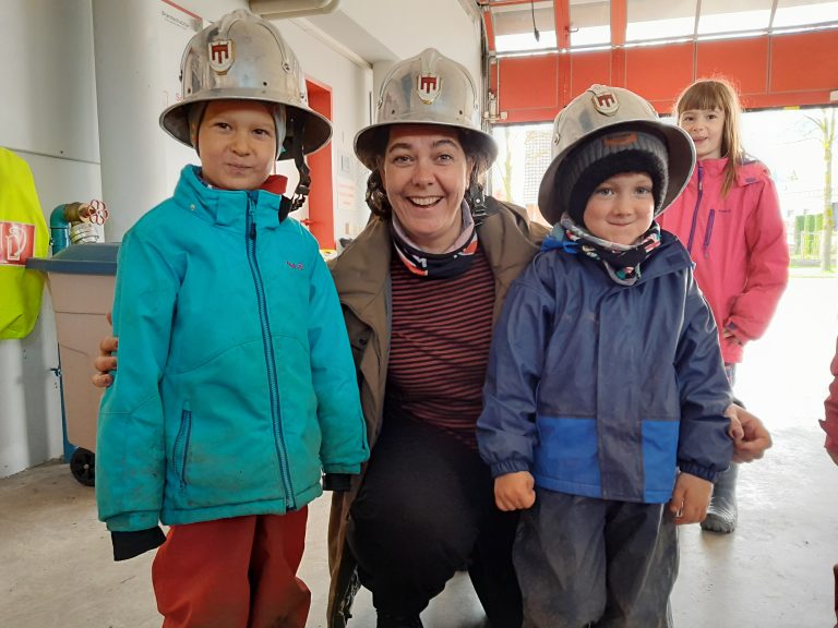 Pädagogin zwischen zwei Kinder bei der Feuerwehr